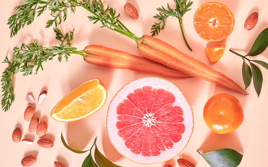unterschiedliche, aufgeschnittene Obst- und Gemüsesorten auf einem leicht rosa Untergrund.