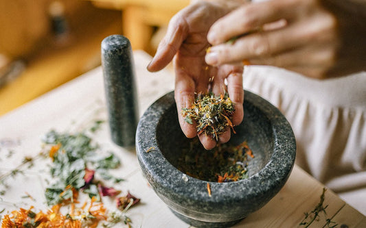 Dunkle Mörserschale mit bunten Kräutern.