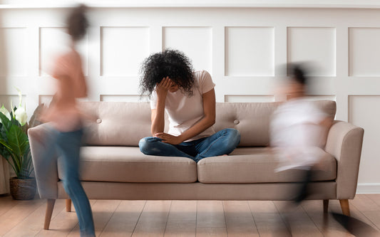 Frau in Stresssituation, im Schneidersitz auf der Couch den Kopf in der Hand abstützend