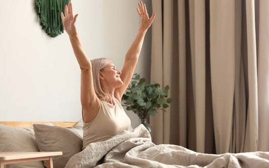 Person streckt sich morgens im Bett nach dem Aufwachen