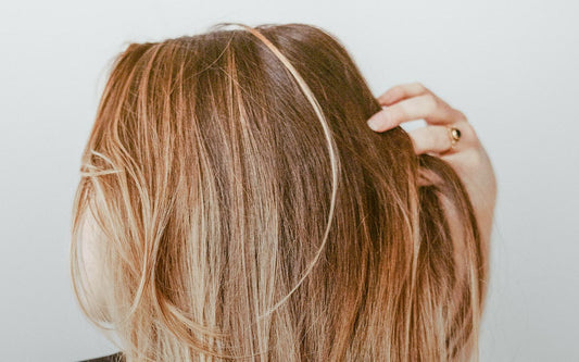 Blonde Frau, die sich mit der Hand durch die Haare fährt. 