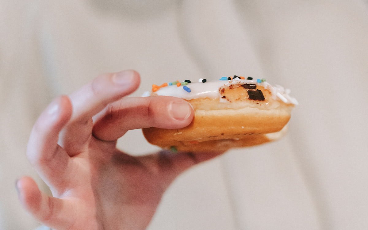 Zuckerglasierter Donut in einer Hand