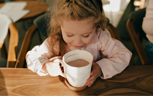 Kind trinkt Heißgetränk mit Kakao aus Tasse