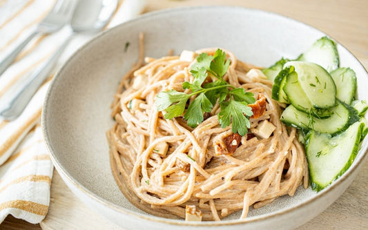 Vegane Spaghetti Carbonara mit Gurkensalat auf einem Teller