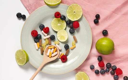 verschiedene Nahrungsergänzungsmittel in Pillenform auf einem Teller mit Limetten dekoriert