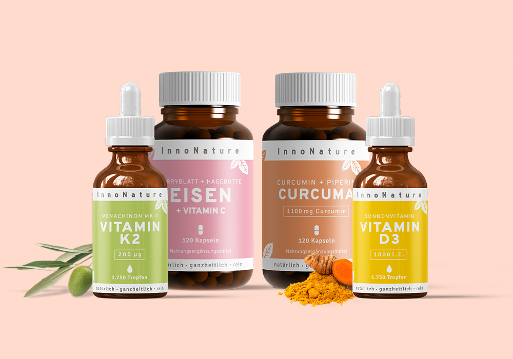 Das Kleine-Wohlfühl-Paket von InnoNature vor einem orangen Hintergrund.Dieses Paket beinhaltet eine hochwirksame Kombination aus Vitamin D3, Vitamin K2, Curcuma und Eisen.