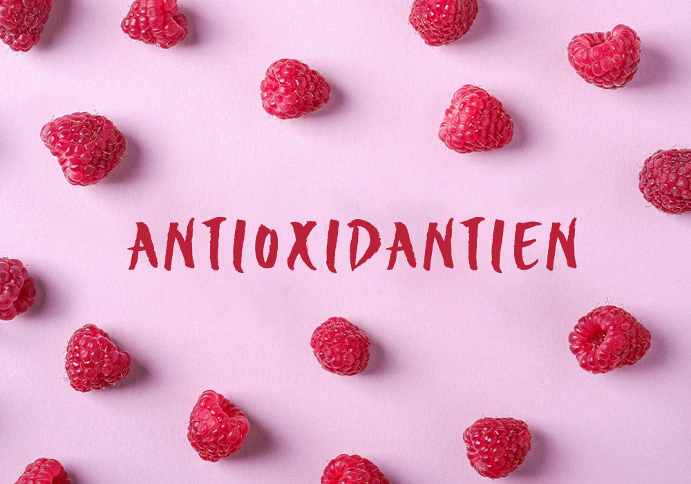 Das Wort "Antioxidantien" auf rosa Hintergrund, dekoriert mit Himbeeren