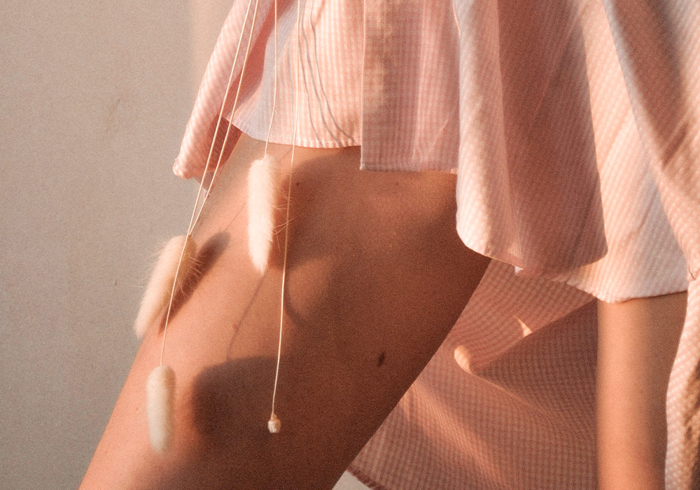 Frau mit rosa Kleid, deren Oberschenkel durch die Sonne bestrahlt wird