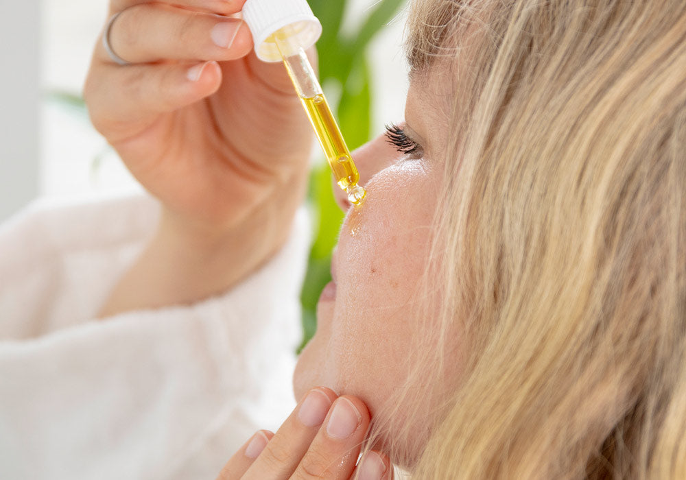 Frau tropft sich Vitamin C Serum auf die Haut.