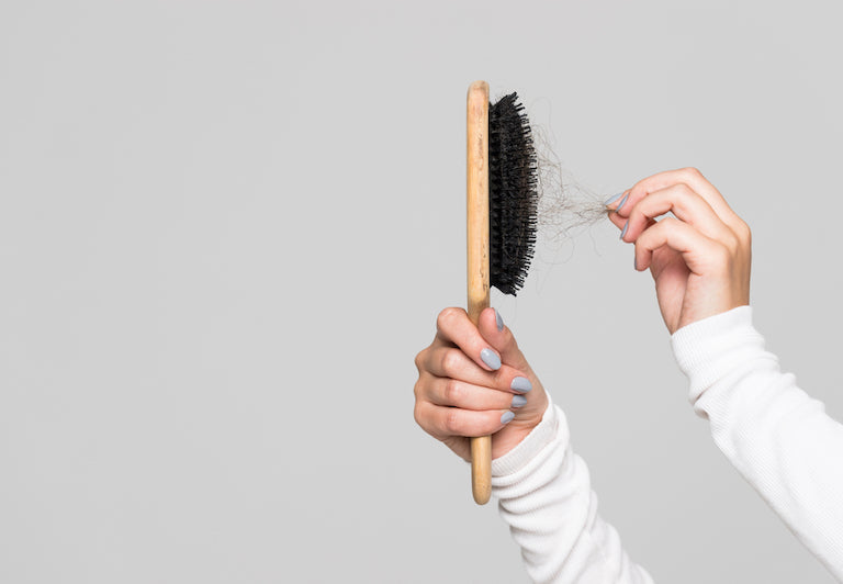 Eine Bürste aus der einige Haare gezogen werden.