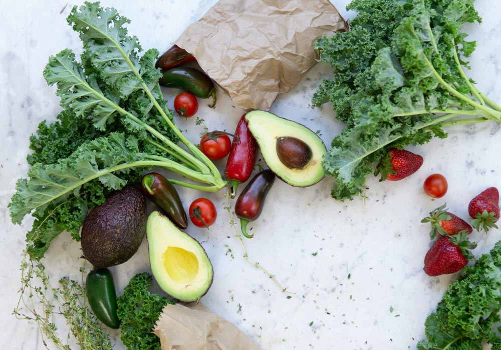 Grünkohl, Avocado, Paprika, Erdbeere auf einem weißen Marmortisch