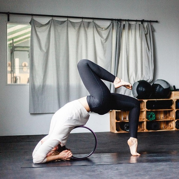 Frau macht Yoga in einem Yoga-Studio auf einem Yoga-Rad